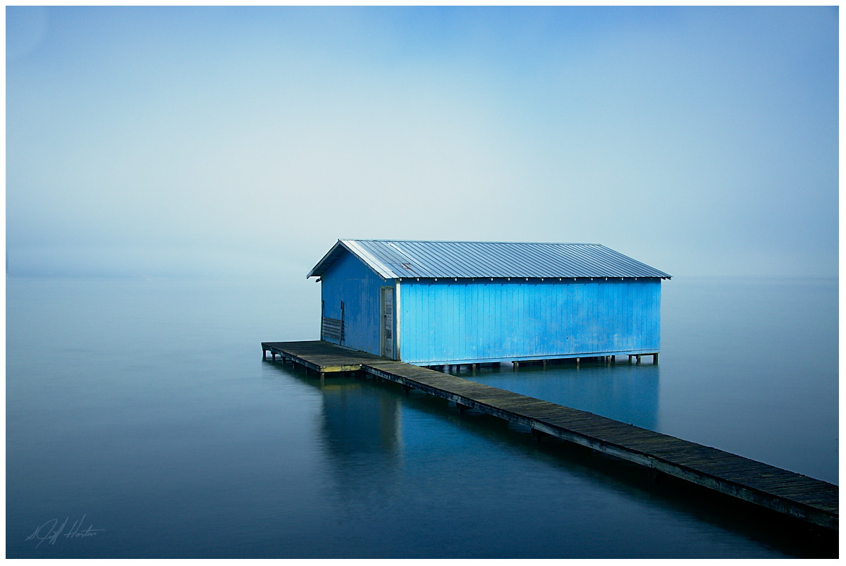 Blue boathouse on a foggy morning